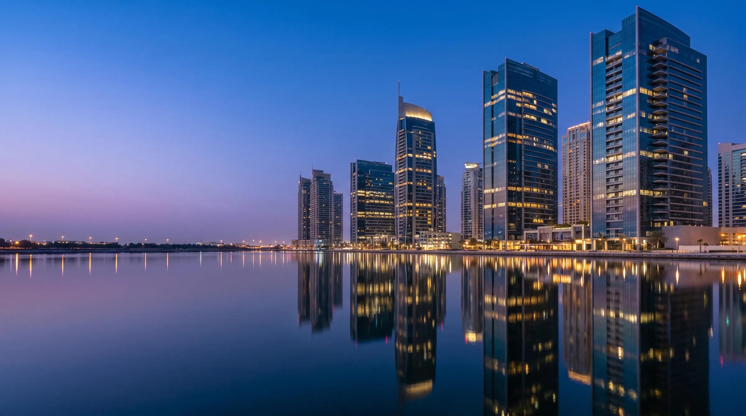 Glass office towers in a Gulf business district at dusk