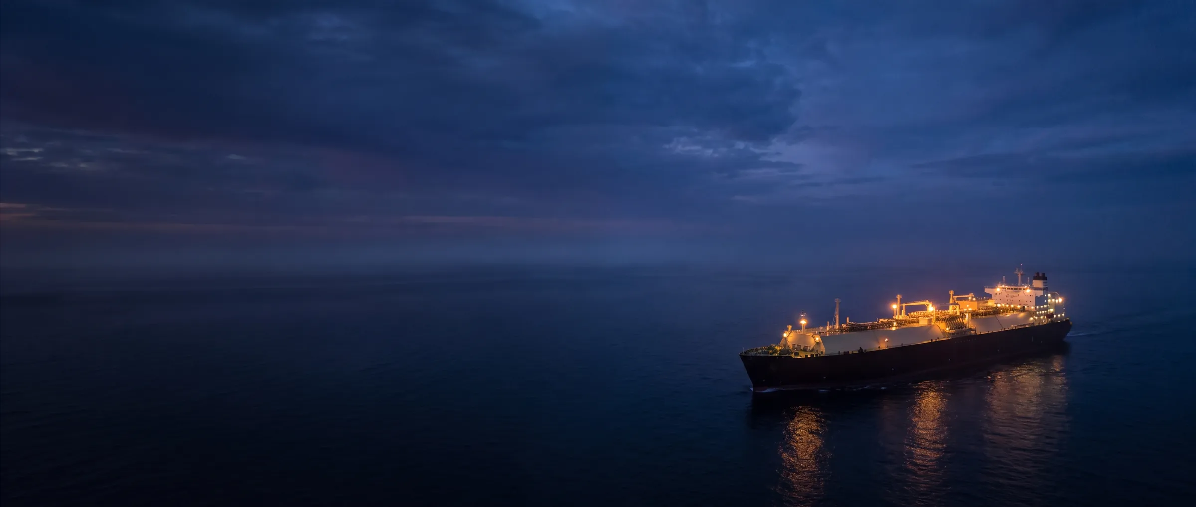 An LNG carrier sailing on a calm sea at blue hour