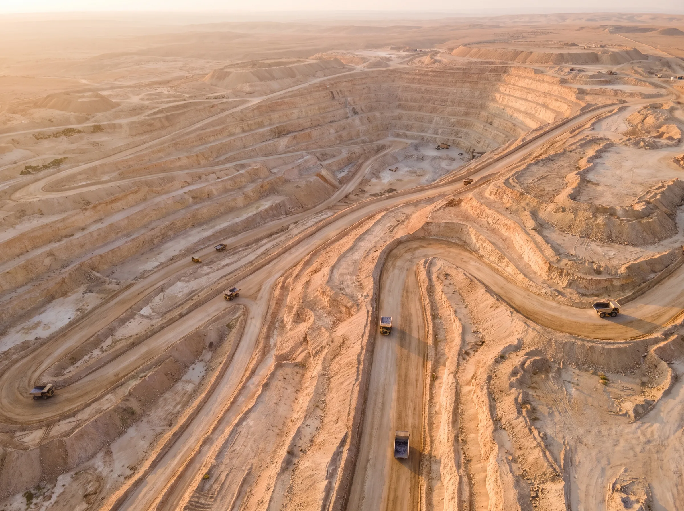 A terraced open pit phosphate mine in the desert at sunrise